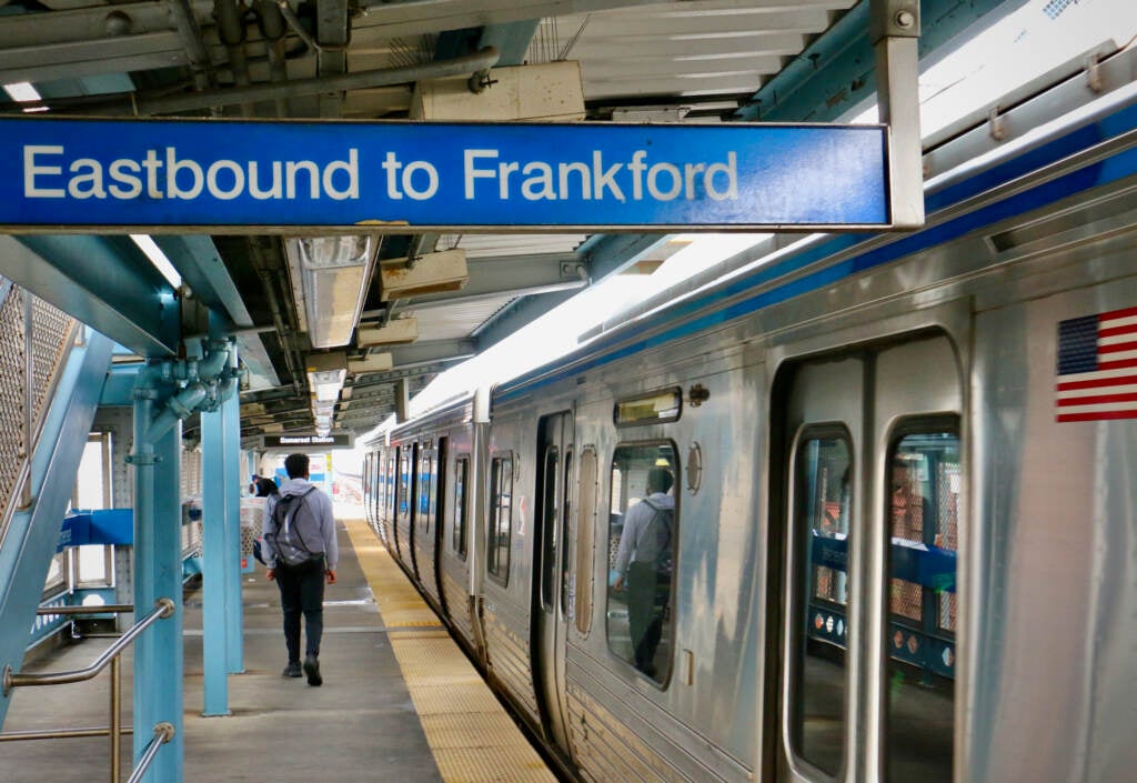 A person walks along a train platform on the left, as a train pulls in on the right.