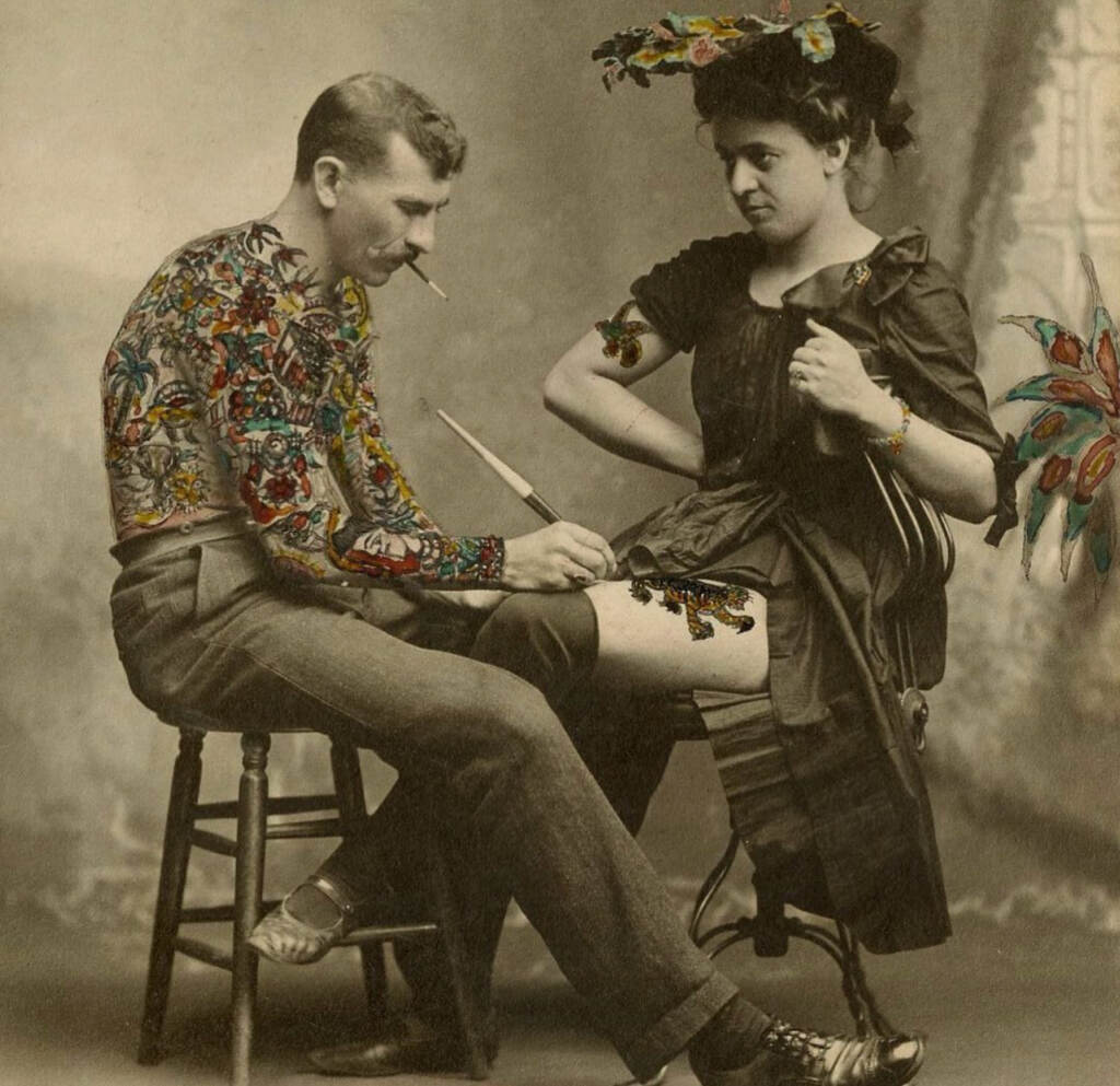 A man inks a tatto on a woman's leg.