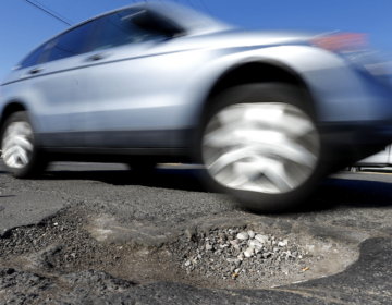 A vehicles drives past a pothole in Philadelphia on Monday, Feb. 24, 2014. Since Dec. 1, 2013, PennDOT workers have applied more than 2,000 tons of patching material in the five counties around the city, according to spokesman Gene Blaum. (AP Photo/Matt Rourke)