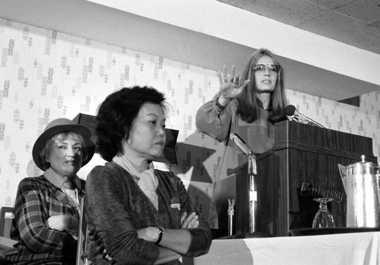 In this Nov. 21, 1979 file photo, Bella Abzug, left, and Patsy Mink of Women USA sit next to Gloria Steinem as she speaks in Washington where they warned presidential candidates that promises for women's rights will not be enough to get their support in the next election. (AP Photo/Harvey Georges)