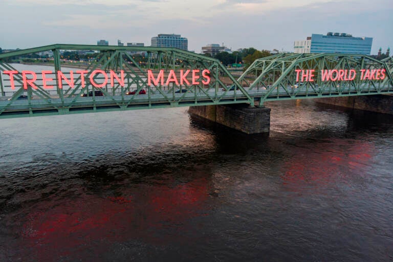 American Manufacturing A bridge over a river with large neon lights spelling out 'Trenton Makes the World Takes''