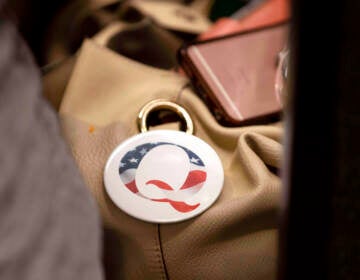 FILE - A QAnon conspiracy theory button sits affixed to the purse of an attendee of the Nebraska Election Integrity Forum on Saturday, Aug. 27, 2022, in Omaha, Neb. Former President Donald Trump is increasingly embracing and endorsing the QAnon conspiracy theory, even as the number of frightening real-world incidents linked to the movement increase. On Tuesday, Sept. 13, 2022, using his Truth Social platform, Trump reposted an image of himself — wearing a Q lapel pin — overlaid with the words “The Storm is Coming.