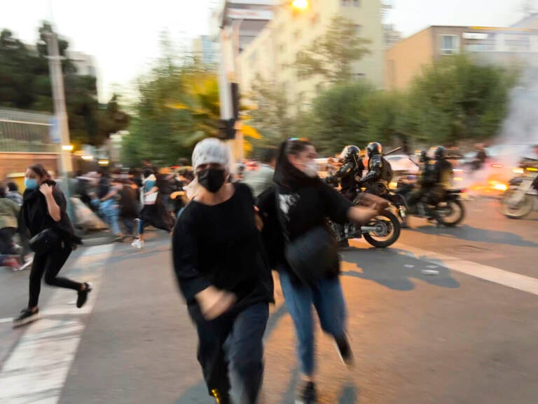 Women run away from anti-riot police during a protest of the death of a young woman who had been detained for violating the country's conservative dress code, in downtown Tehran, Iran. (AP Photo)