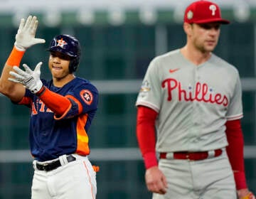 An Astros player celebrates as a blurry Phillies player looks dejected in the foreground.