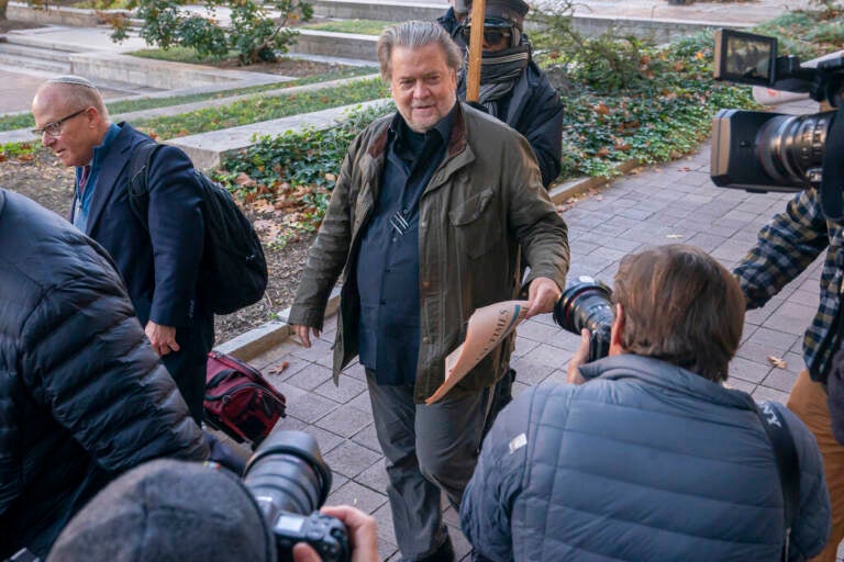 Steve Bannon is surrounded by reporters outside of a courtroom.