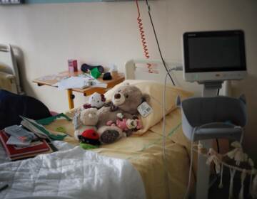 Several stuffed animals sit on a n empty hospital bed.