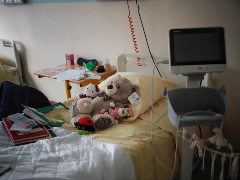 Several stuffed animals sit on a n empty hospital bed.