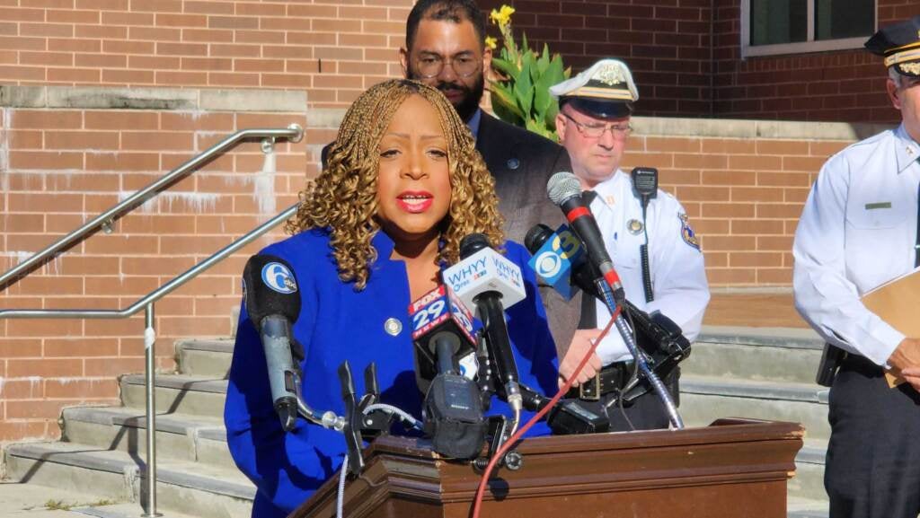 Councilmember Jamie Gauthier speaks into microphones at a podium.