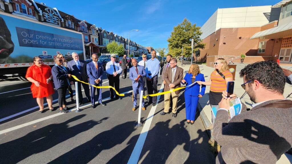 A bunch of people are gathered around a recently cut yellow ribbon.