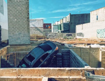 A car sticks out of a hole in a construction site.