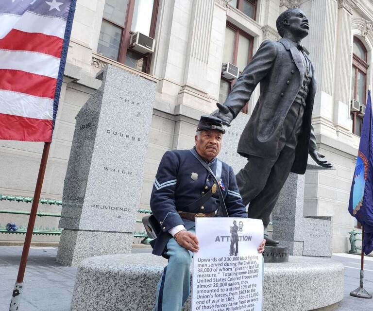 Robert Fuller Houston of the 3rd Regiment sits by the Catto statue at City Hall on Oct. 10, 2022. (Tom MacDonald/WHYY)