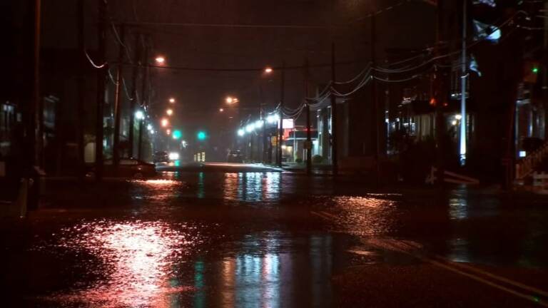 A flooded roadway is shown at night.