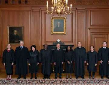 The U.S. Supreme Court Justice stand facing the camera in their court attire.