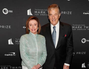 Nancy Pelosi stands next to her husband.