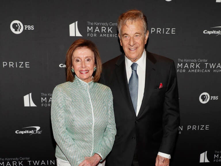 Nancy Pelosi stands next to her husband.