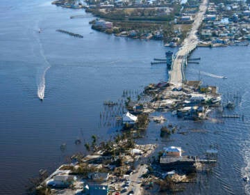 An aerial view shows a damaged bridge that has sunk into the water.