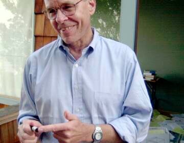 K. Barry Sharpless points to a sample used in his work, as he stands on the balcony outside of his home office