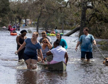 People wade through a flooded road.