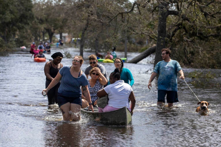 People wade through a flooded road.