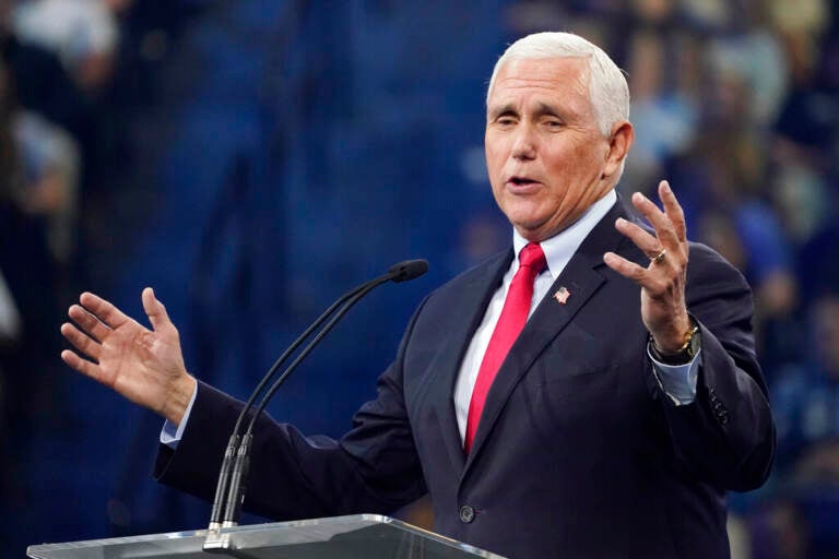 Mike Pence speaks at a podium with his hands raised.