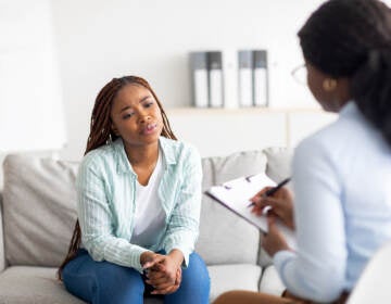 A woman sits on a couch in front of a therapist.