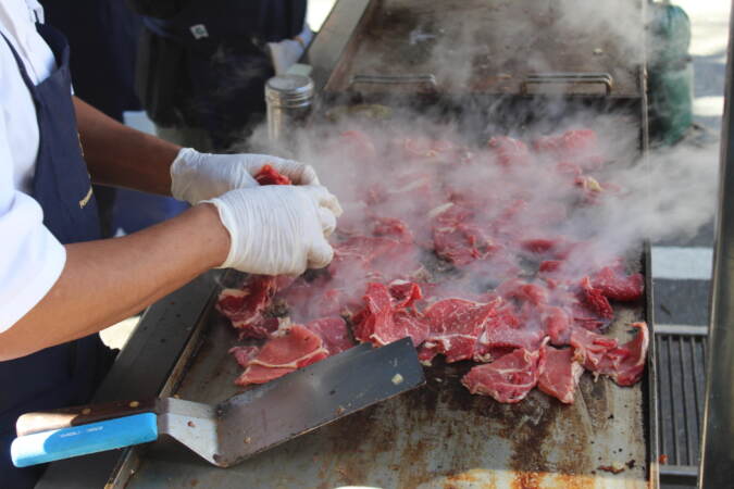 A close-up of someone cooking some sort of meat on a grill.