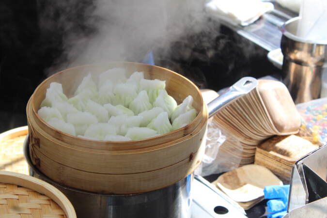 Steam rises off of a basket of dumplings.