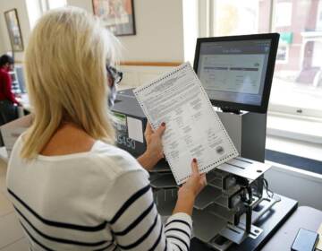 A person holds a mail ballot in their hand.