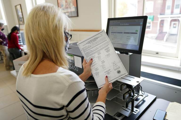 A person holds a mail ballot in their hand.