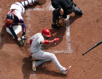 Philadelphia Phillies right fielder Nick Castellanos (8) scores against Atlanta Braves catcher Travis d'Arnaud (16) during the third inning in Game 1 of a National League Division Series baseball game, Tuesday, Oct. 11, 2022, in Atlanta. (AP Photo/John Bazemore)