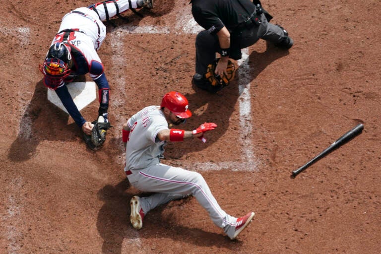 Philadelphia Phillies right fielder Nick Castellanos (8) scores against Atlanta Braves catcher Travis d'Arnaud (16) during the third inning in Game 1 of a National League Division Series baseball game, Tuesday, Oct. 11, 2022, in Atlanta. (AP Photo/John Bazemore)