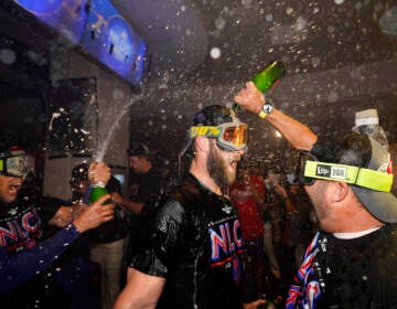 Philadelphia Phillies Bryce Harper, center, is doused in booze in the locker room