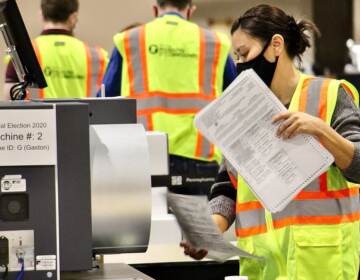 An election worker holds a mail ballot.