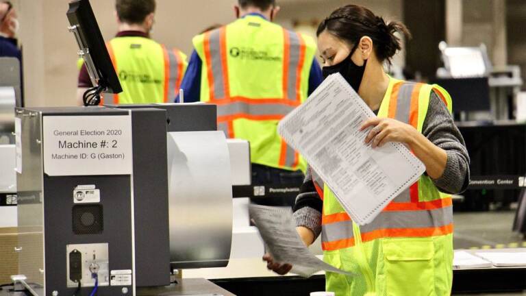 An election worker holds a mail ballot.