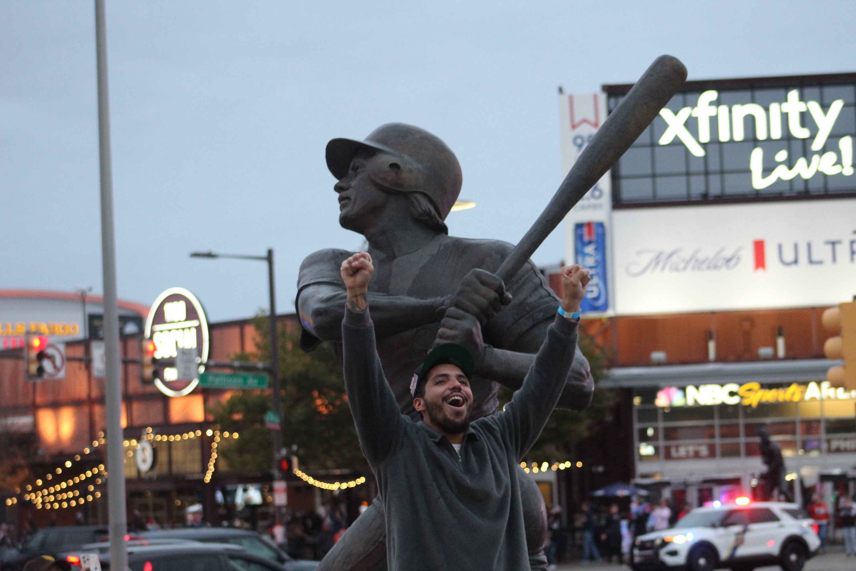 A man raises his arms in front of the Steve Carlton statue outside of Citizens Bank Park.