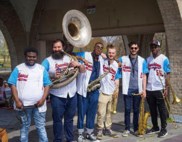 Members of the Philly band Snacktime pose with Phillies jerseys on, instruments in hand.