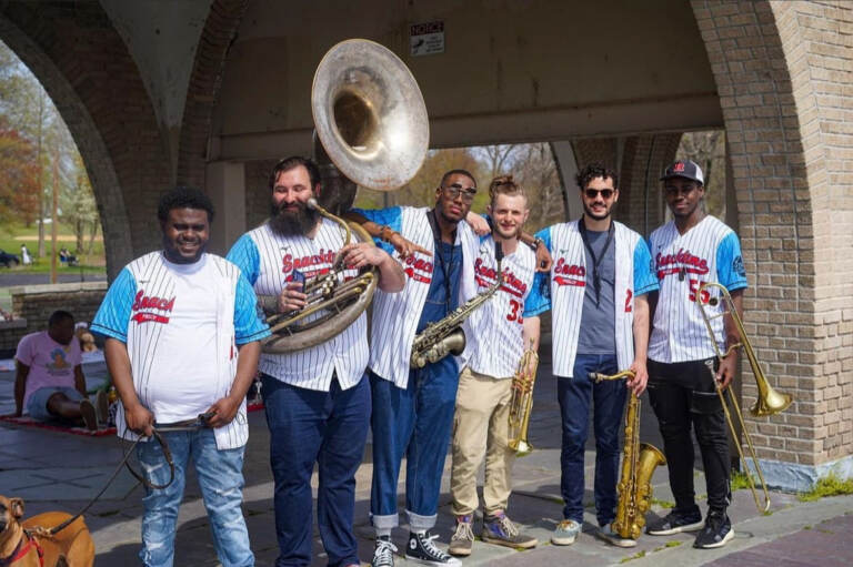 Members of the Philly band Snacktime pose with Phillies jerseys on, instruments in hand.