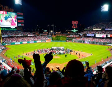 A silhouette of fans cheering as the Phillies celebrate on the field at Citizens Bank Park.