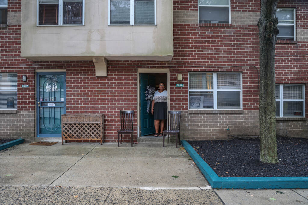 A woman stands at the door of her apartment.