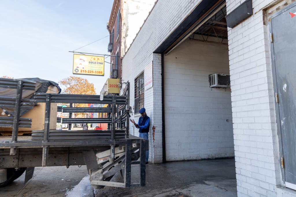 A man stands outside of a garage entryway.