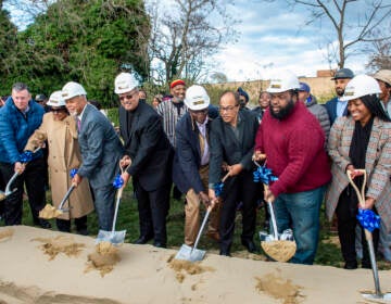 People hold shovels and break ground at a ceremonial opening.