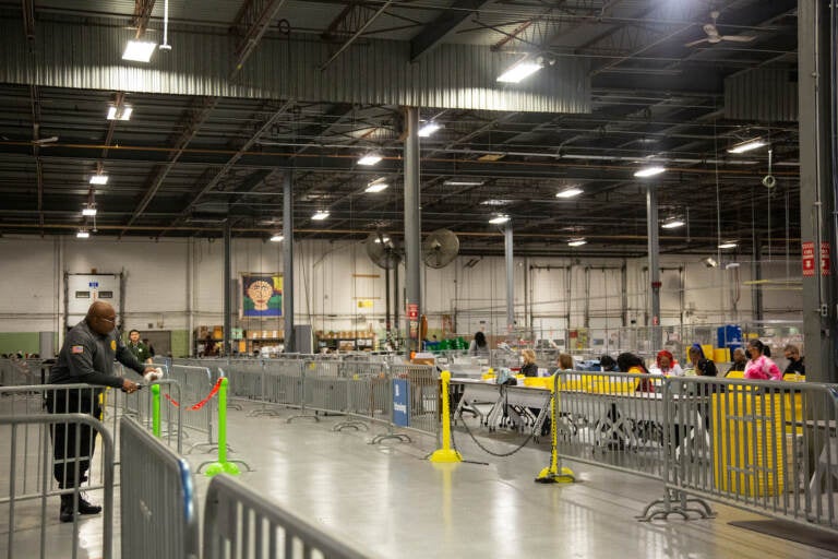 A large warehouse is shown, with election workers working to process mail ballots.