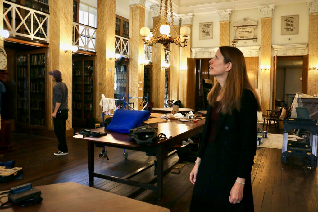 A person stands in the middle of a room undergoing renovations, looking upward.