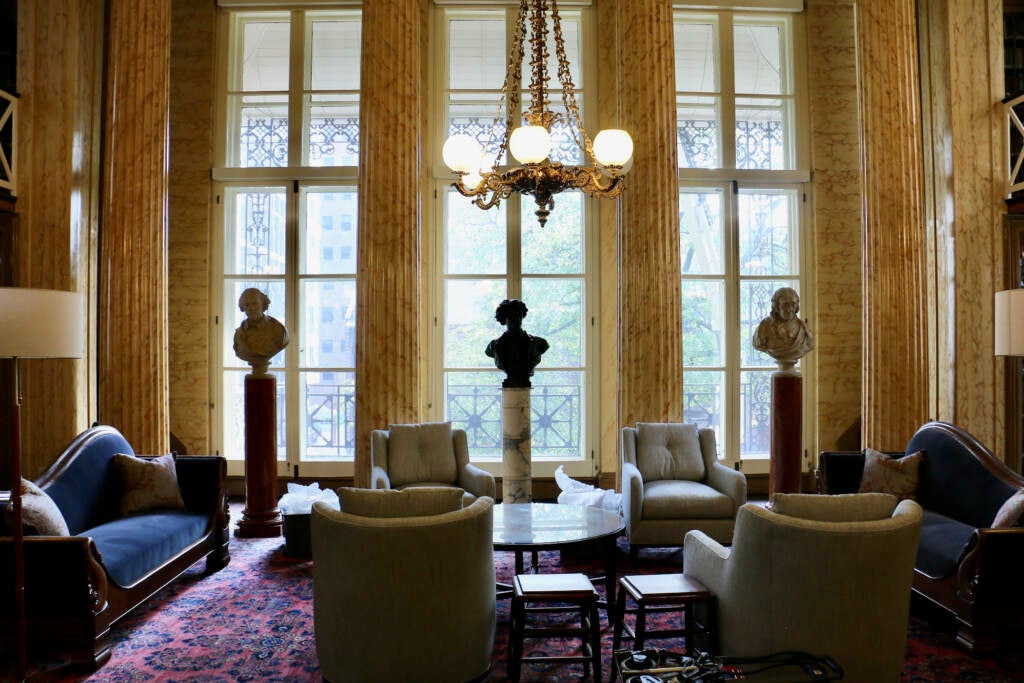 Light shines through tall windows in an ornate room.