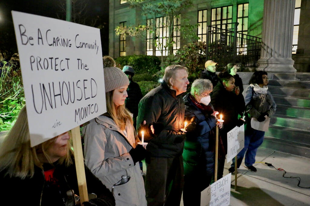 People hold candles at night in the cold.