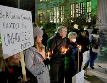 People hold candles at night in the cold.