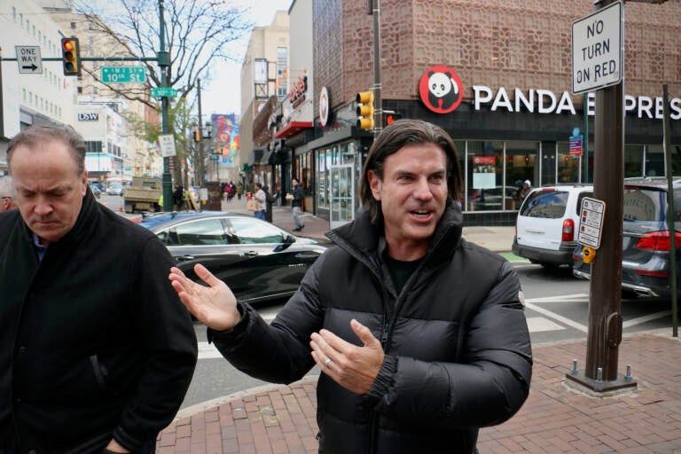 David Adelman, part owner of the Philadelphia 76ers, stands at the corner of 10th and Market streets, across the street from where the team hopes to build a new arena (Emma Lee/WHYY)