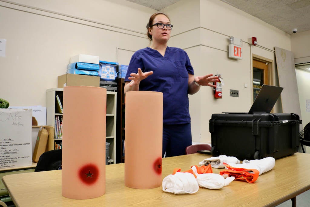 A nurse stands at the front of a room giving instructions.