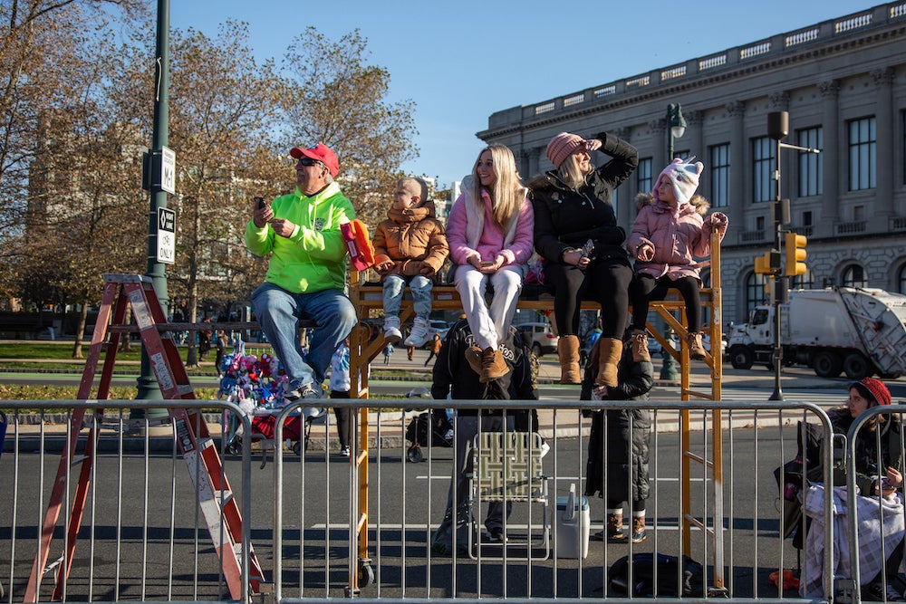 2022 24 011 – e cohen – Thanksgiving day parade-3381 As long as the weather permits, the Pilawsky Hueston family has the best seats on the parade route thanks to their scaffolding bench at the 103rd Philadelphia Thanksgiving Day Parade. (Emily Cohen for WHYY)