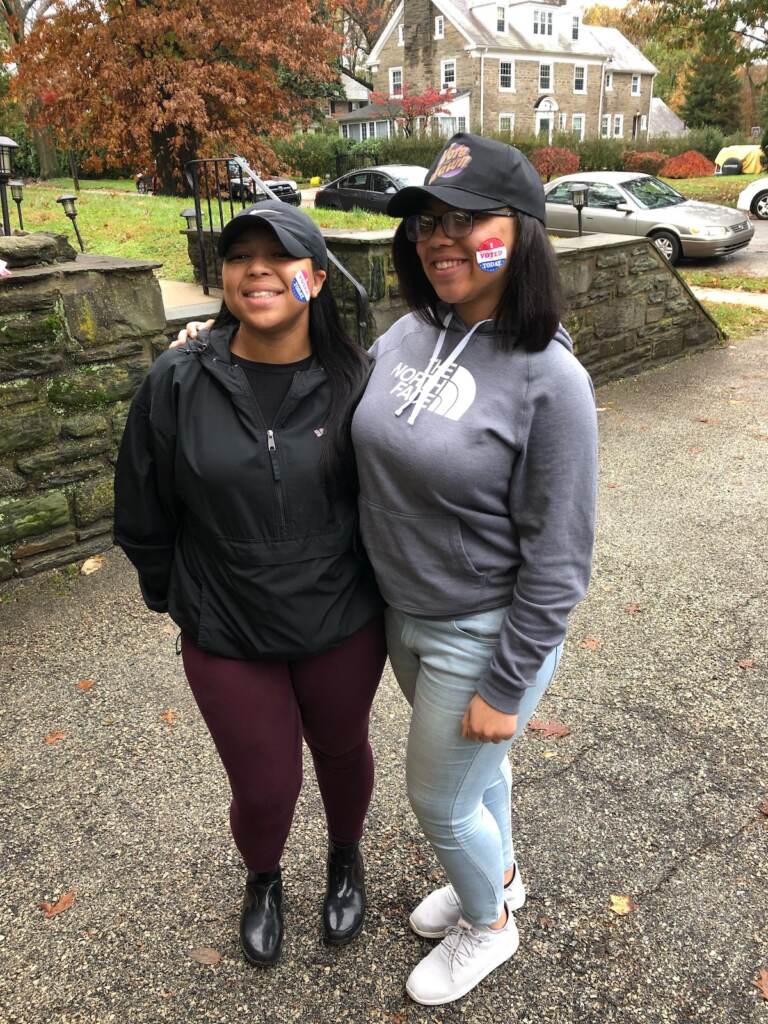 Two people pose, smiling, with I Voted stickers visible on their cheeks.